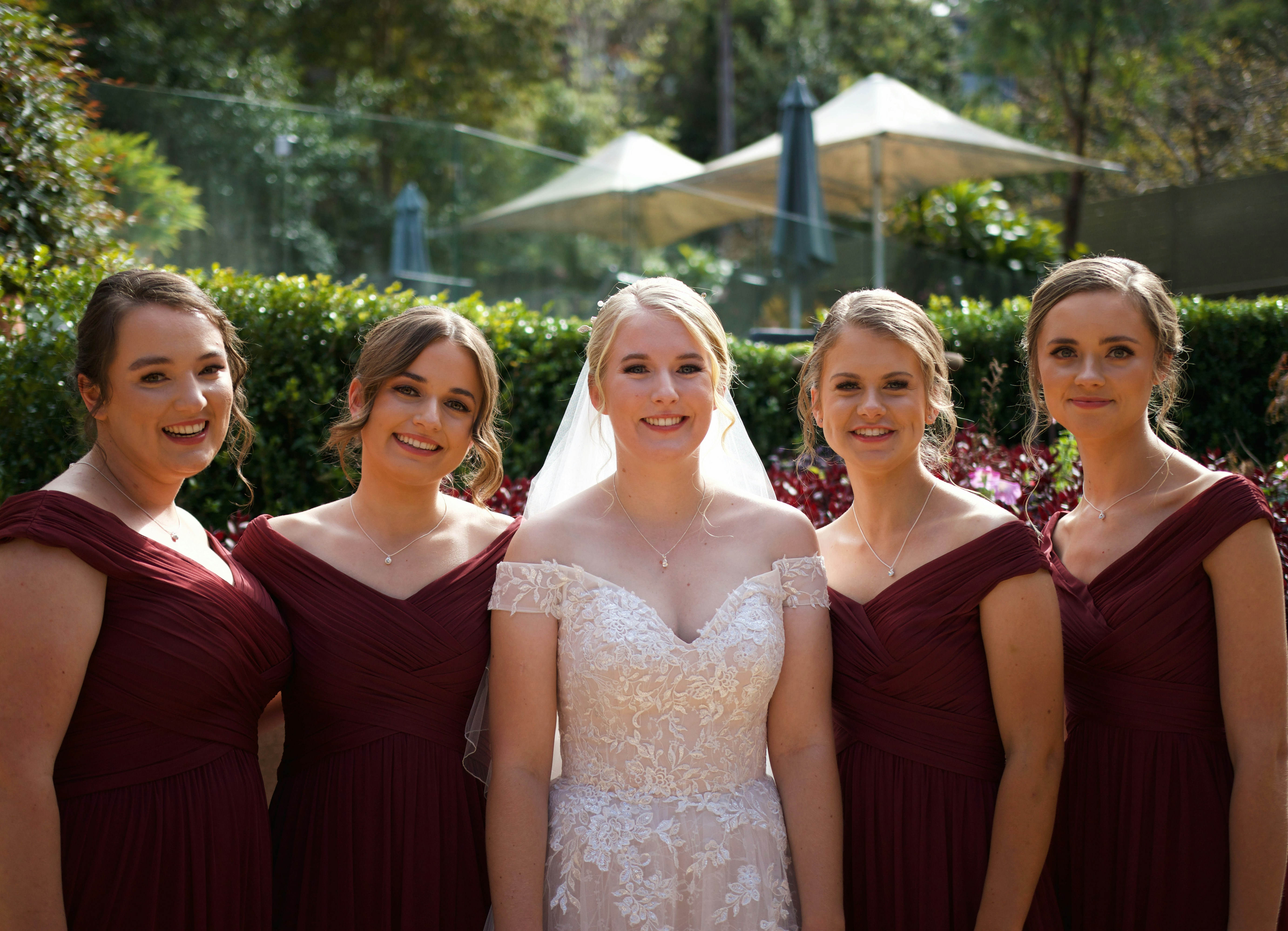 bride in lace gown with two brides maids in red gowns